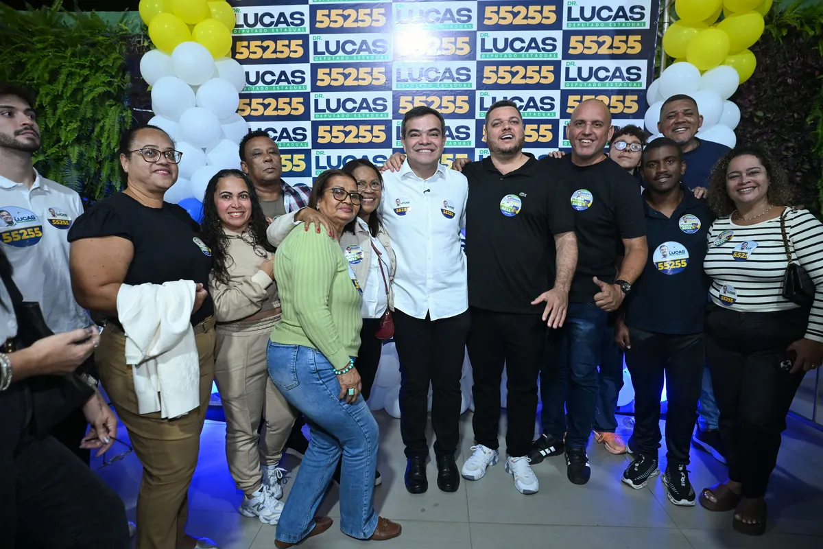 Dr. Lucas 55255 no meio de um grupo grande de apoiadores no painel da campanha