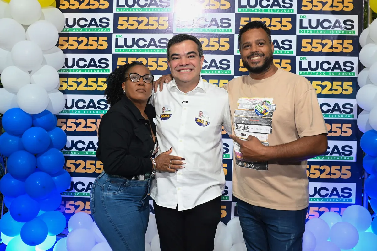 Dr. Lucas 55255 entre dois apoiadores no painel da campanha