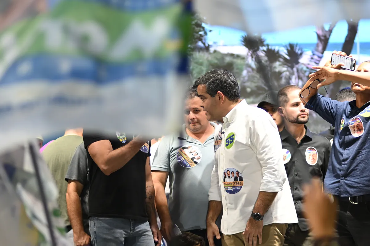 Dr. Lucas 55255 cercado por apoiadores e bandeiras, com celulares registrando o momento