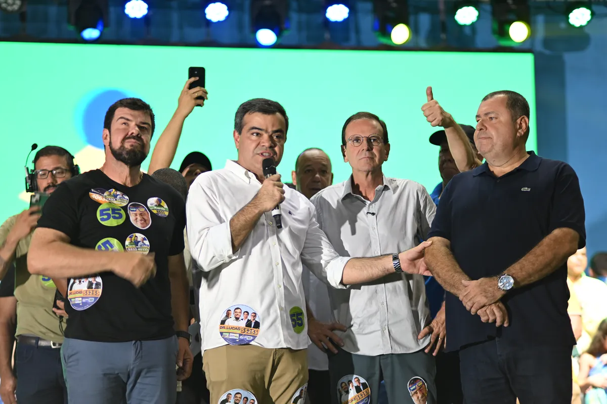 Dr. Lucas 55255 discursa no palco, com apoiadores e candidatos em volta