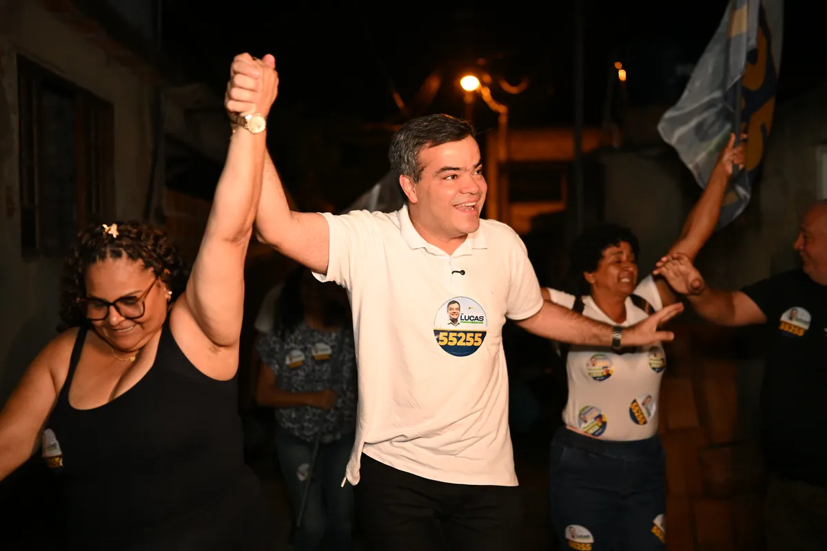 Dr. Lucas 55255 de mãos dadas e braços erguidos com apoiadoras em Lagomar