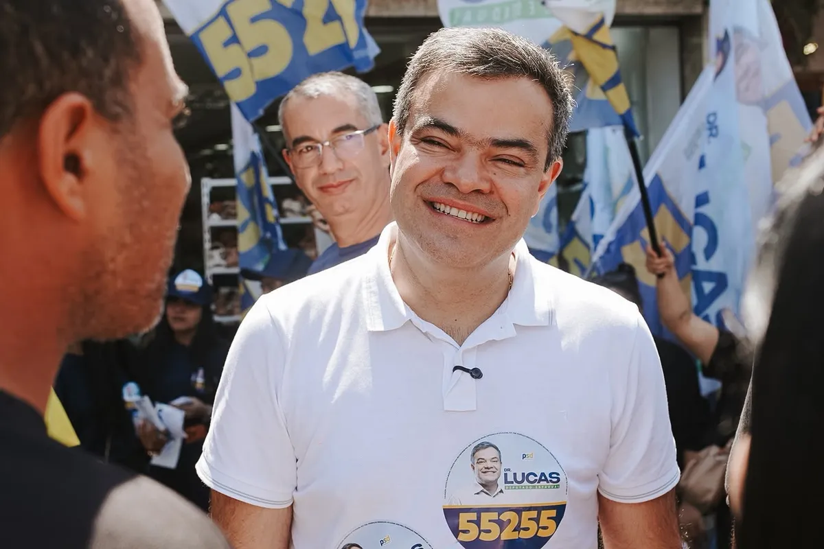 Dr. Lucas 55255 sorridente entre apoiadores, com bandeiras da campanha ao fundo, em Rio das Ostras