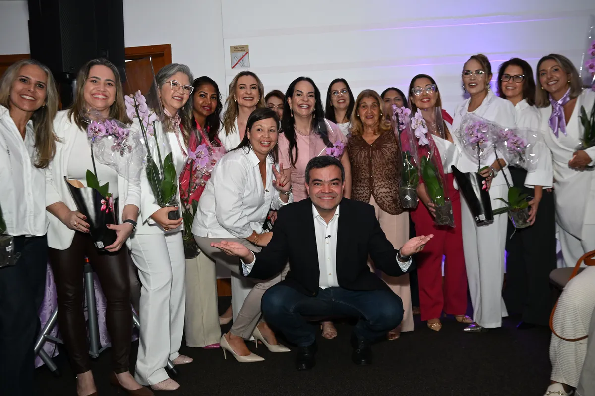 Dr. Lucas 55255 agachado à frente de dezenas de mulheres com orquídeas, ao fim do encontro