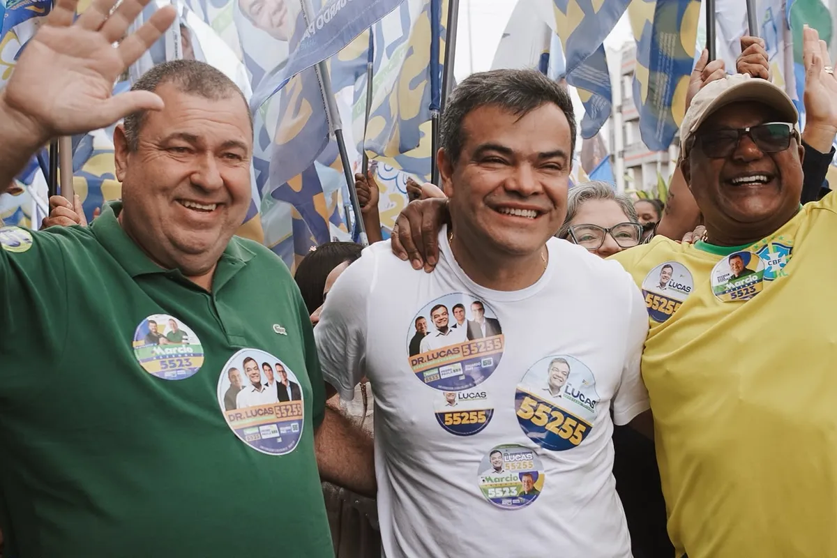 Dr. Lucas 55255 entre duas lideranças de Rio das Ostras, com as bandeiras da campanha atrás