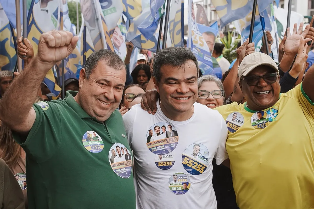 Dr. Lucas 55255 e lideranças locais de braços erguidos, cercados de bandeiras, em Rio das Ostras
